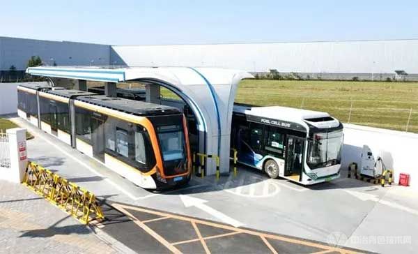 一辆氢能中运量公交车(左)驶入氢能公交车加气站(无人机照片)